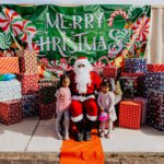 A group of children standing around santa clause.