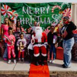 A group of people standing around santa clause.