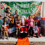 A group of people standing around santa clause.