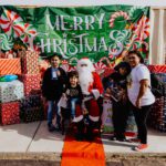 A group of people standing around santa clause.