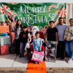 A group of people standing around santa clause.