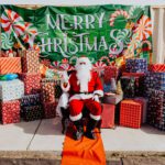 A santa clause sitting in front of many presents.