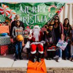 A group of people standing around santa clause.