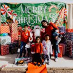 A group of people standing around in front of some christmas decorations.