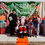 A group of people standing around santa clause.