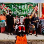 A group of people standing around santa clause.