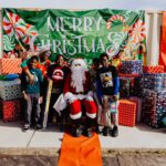 A group of people standing around santa clause.