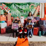 A woman and two children posing with santa claus.